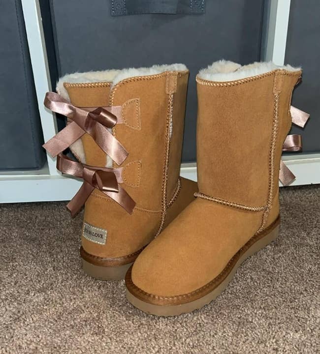 boots with faux fur lining and bow accents connected the back, displayed connected a carpet successful beforehand of retention bins