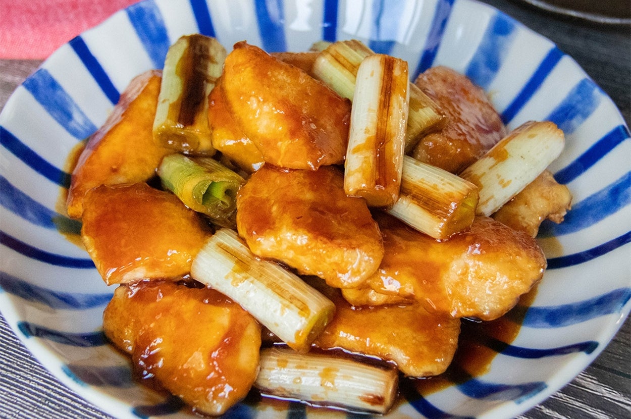 青い縞模様の器に盛られた照り焼きチキンとネギの料理。食欲をそそる見た目です。