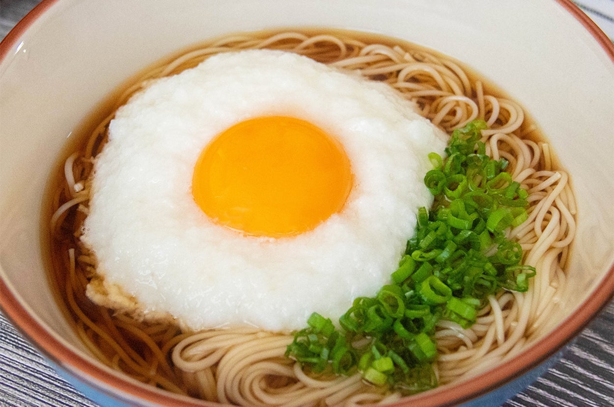 そうめんの上にとろろと卵黄がのり、小ネギが添えられている。