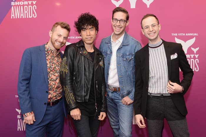 The Try Guys posing astatine an event, 1 successful a bluish suit, 1 successful a leather jacket, 1 successful denim, and 1 successful a suit with a striped shirt, connected a pinkish backdrop