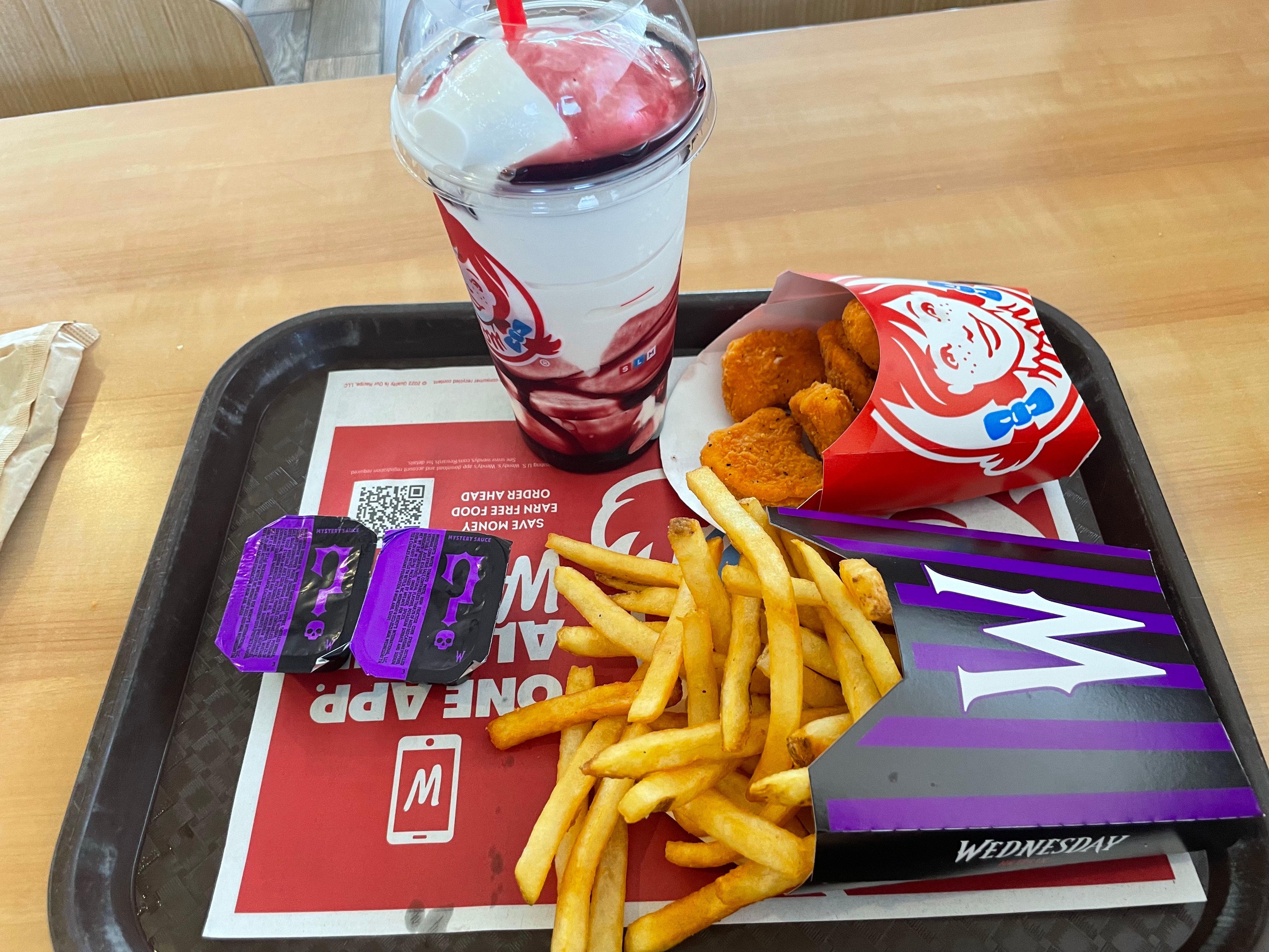 Fast food tray with a drink, nuggets, fries, and a small burger box on a table