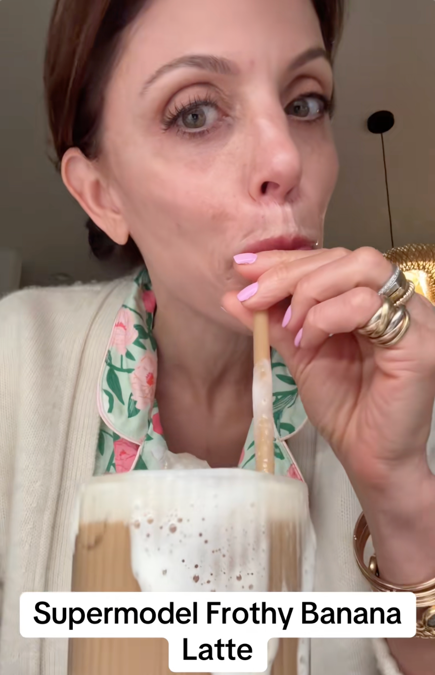 Person sipping a frothy banana latte with floral outfit visible; text reads "Supermodel Frothy Banana Latte."