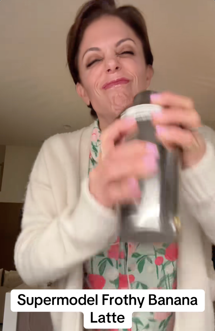Person shaking a blender, wearing a floral-patterned top and cardigan, with text "Supermodel Frothy Banana Latte" displayed below