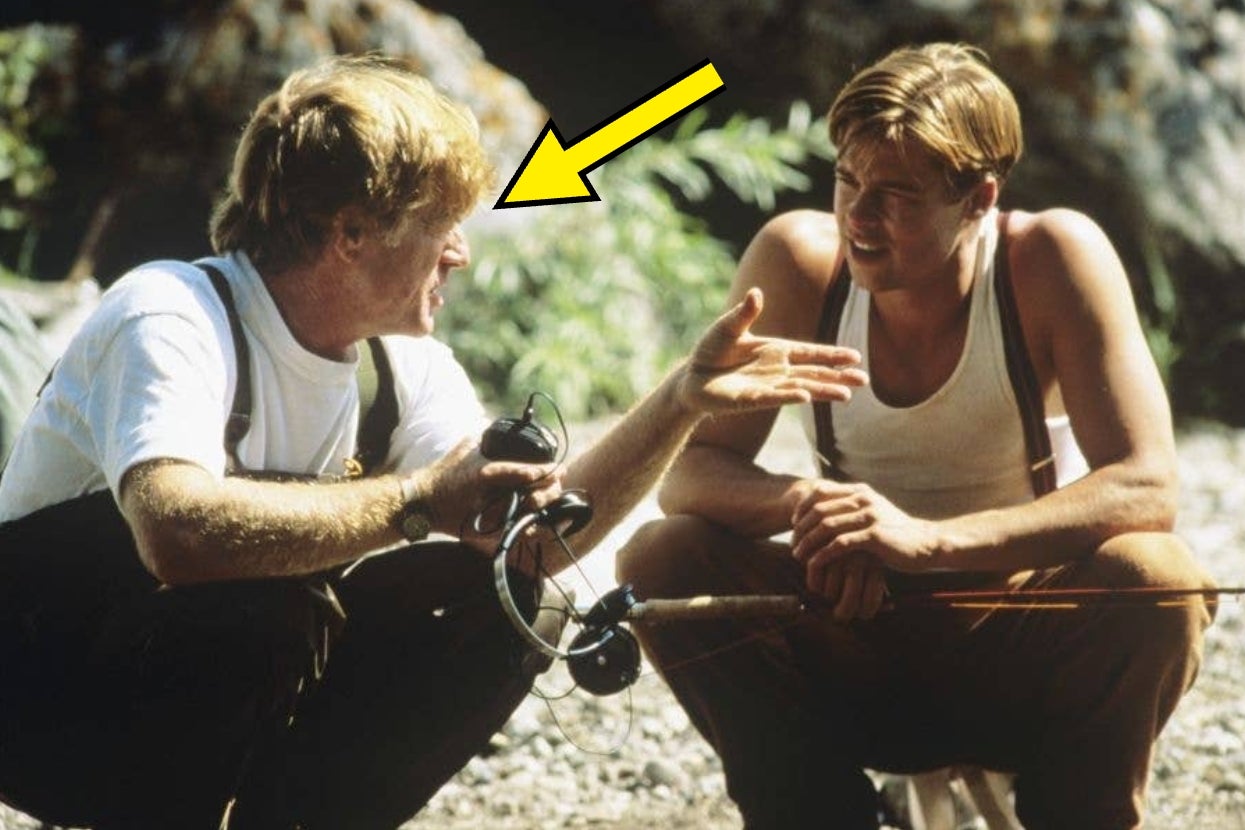 Two actors sit outdoors holding fishing gear. One gestures animatedly while the other listens attentively. An arrow points to the gesturing actor
