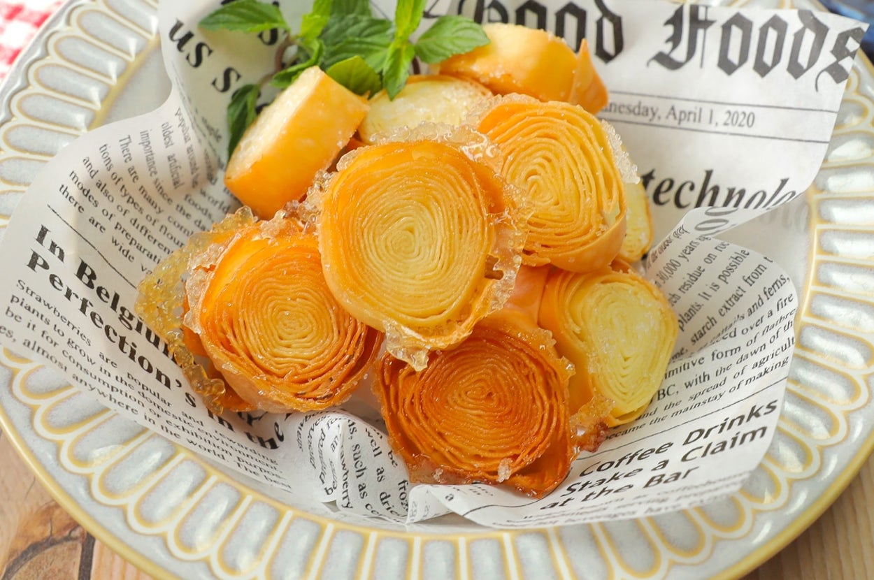 新聞風の紙に盛られたバウムクーヘンのスライス。食欲をそそるプレゼンテーション。
