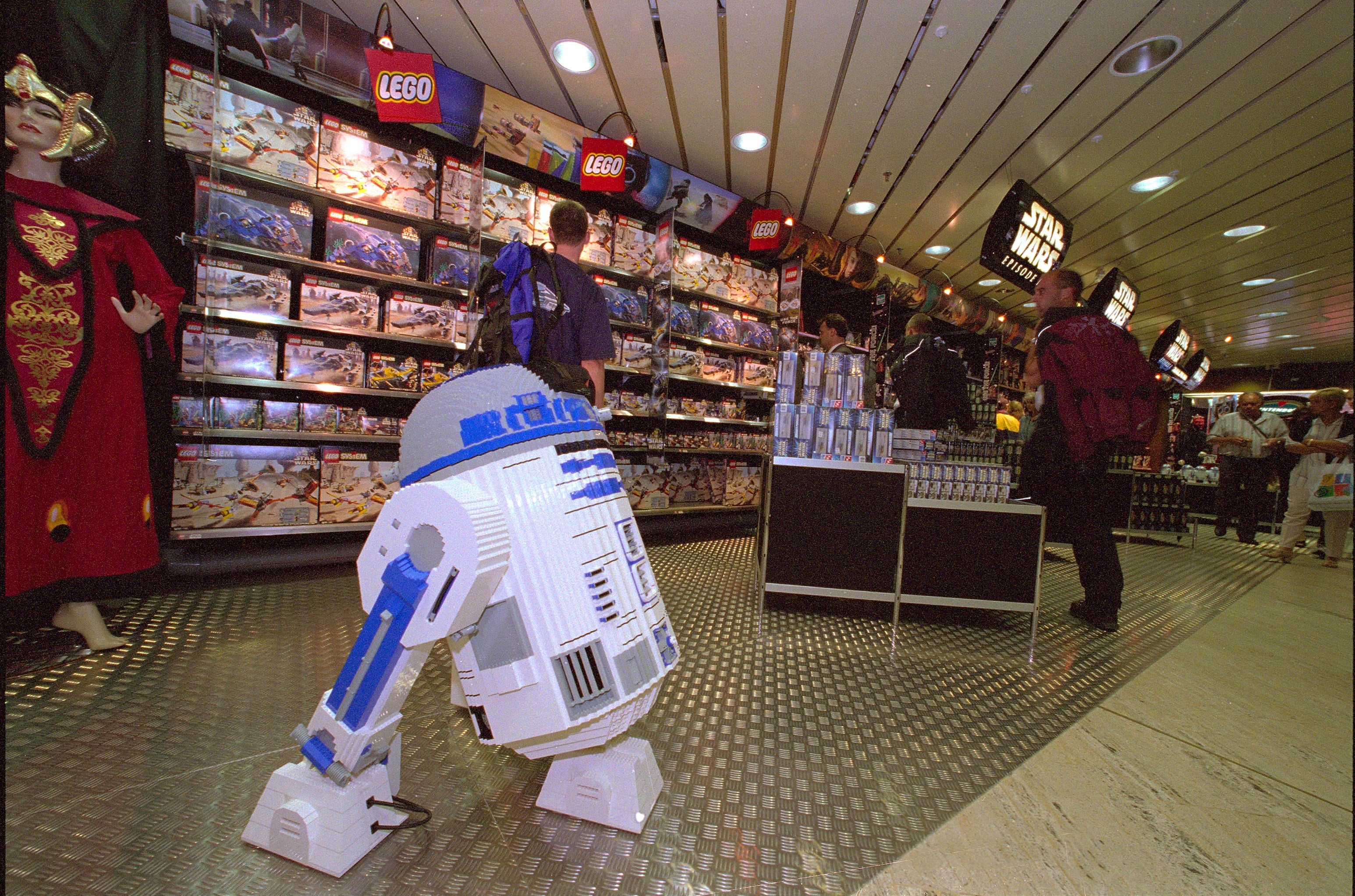 A Star Wars-themed store with LEGO sets connected show features an R2-D2 exemplary and shoppers browsing