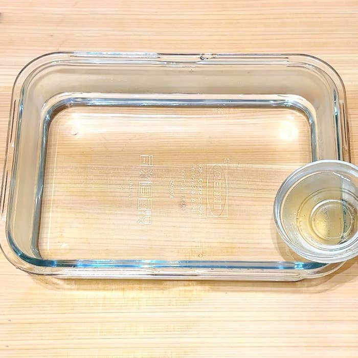 ガラスの容器と、その中の小さなカップが木製のテーブルに置かれています。