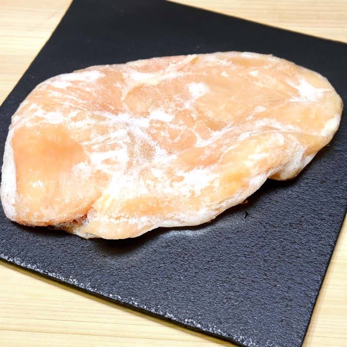 冷凍された鶏胸肉の一枚が黒いプレートの上に置かれている。