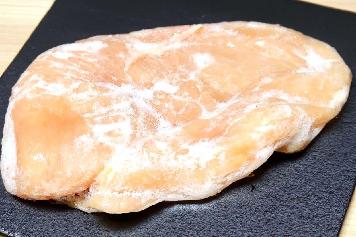 凍った鶏の胸肉が黒い皿に乗っている。