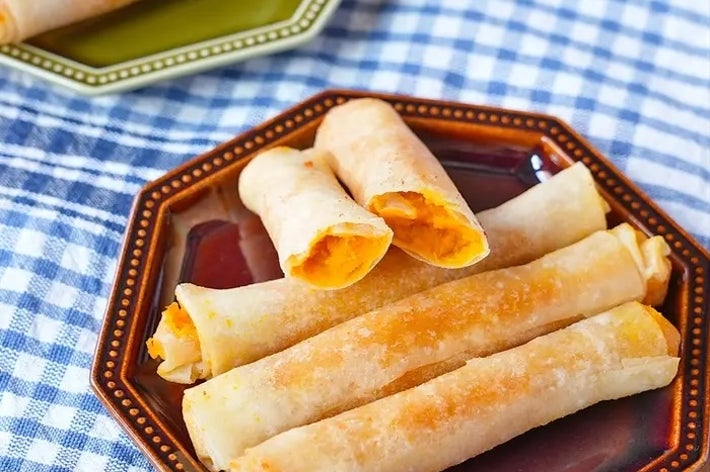 プレートに盛られた春巻き風おつまみ。中身はチーズ風で、サクサクした見た目が食欲をそそる。テーブルクロスが敷かれている。