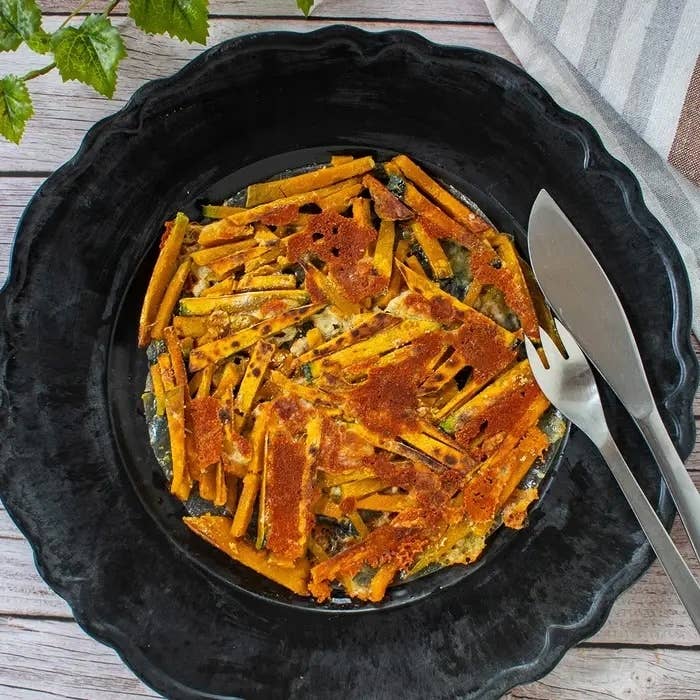 大皿に盛られた、焼き色が付いた棒状の料理が並べられた皿。フォークとナイフが添えられている。