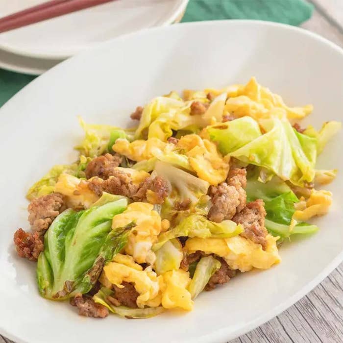 キャベツ、卵、ひき肉の炒め物が白い皿に盛られている。シンプルで家庭的な料理。