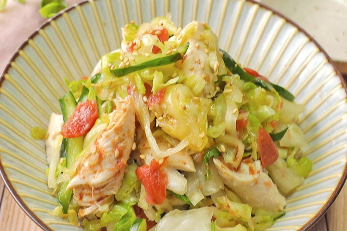 美しく盛り付けられた野菜と鶏肉のサラダが皿にのせられ、隣に小さな白い皿が見える。