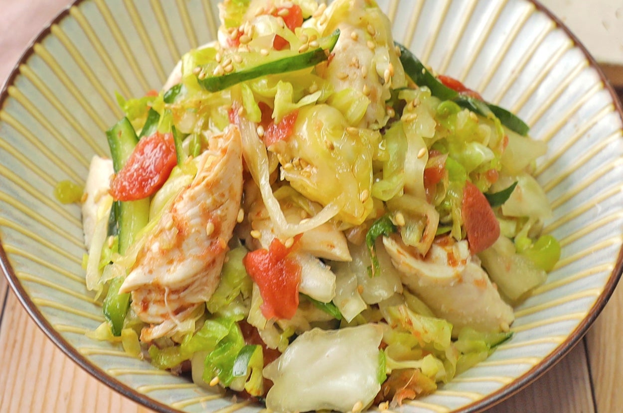 美しく盛り付けられた野菜と鶏肉のサラダが皿にのせられ、隣に小さな白い皿が見える。