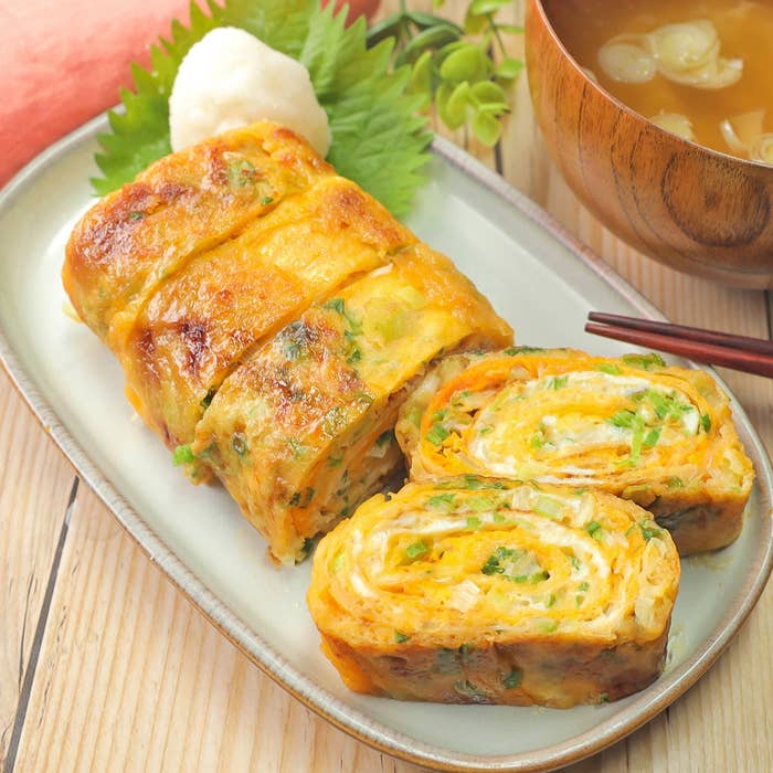 お皿に盛られた出汁巻き卵と味噌汁。刻みネギが混ぜ込まれている。食事の準備が整った様子。
