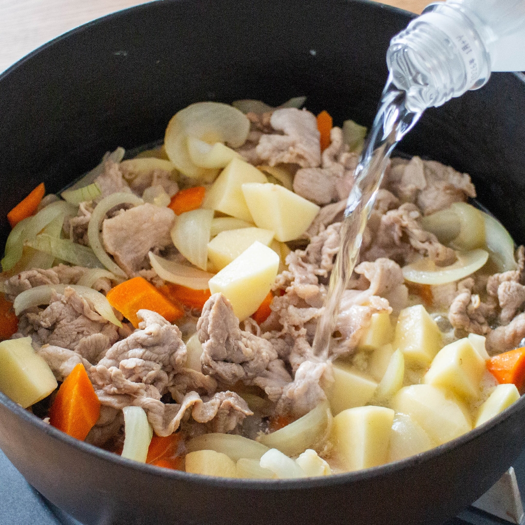 鍋にじゃがいも、にんじん、玉ねぎ、肉が入っており、水が注がれている。