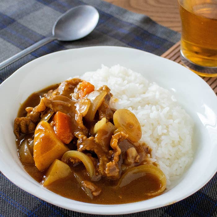 カレーライスの皿とグラスに入った飲み物がテーブルに置かれています。
