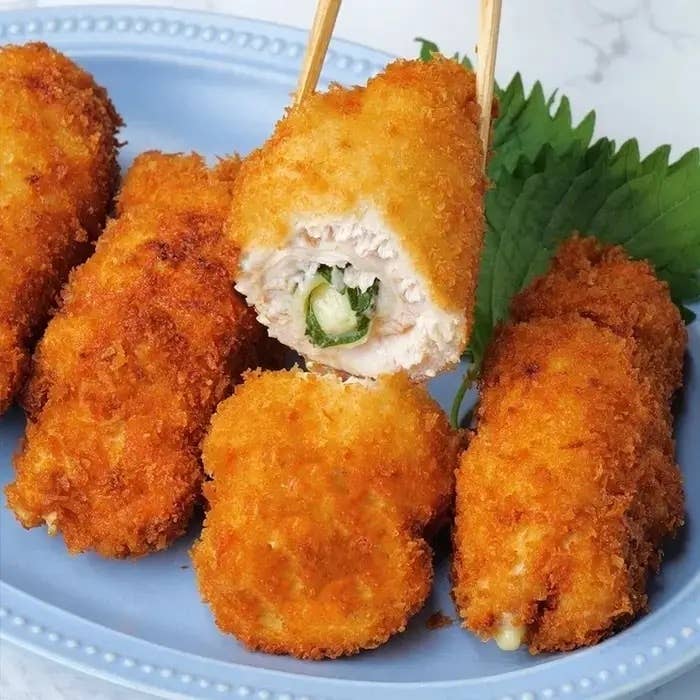 お皿に盛られた数個の揚げた食材があり、一つは箸で持ち上げられて中の具材が見えています。