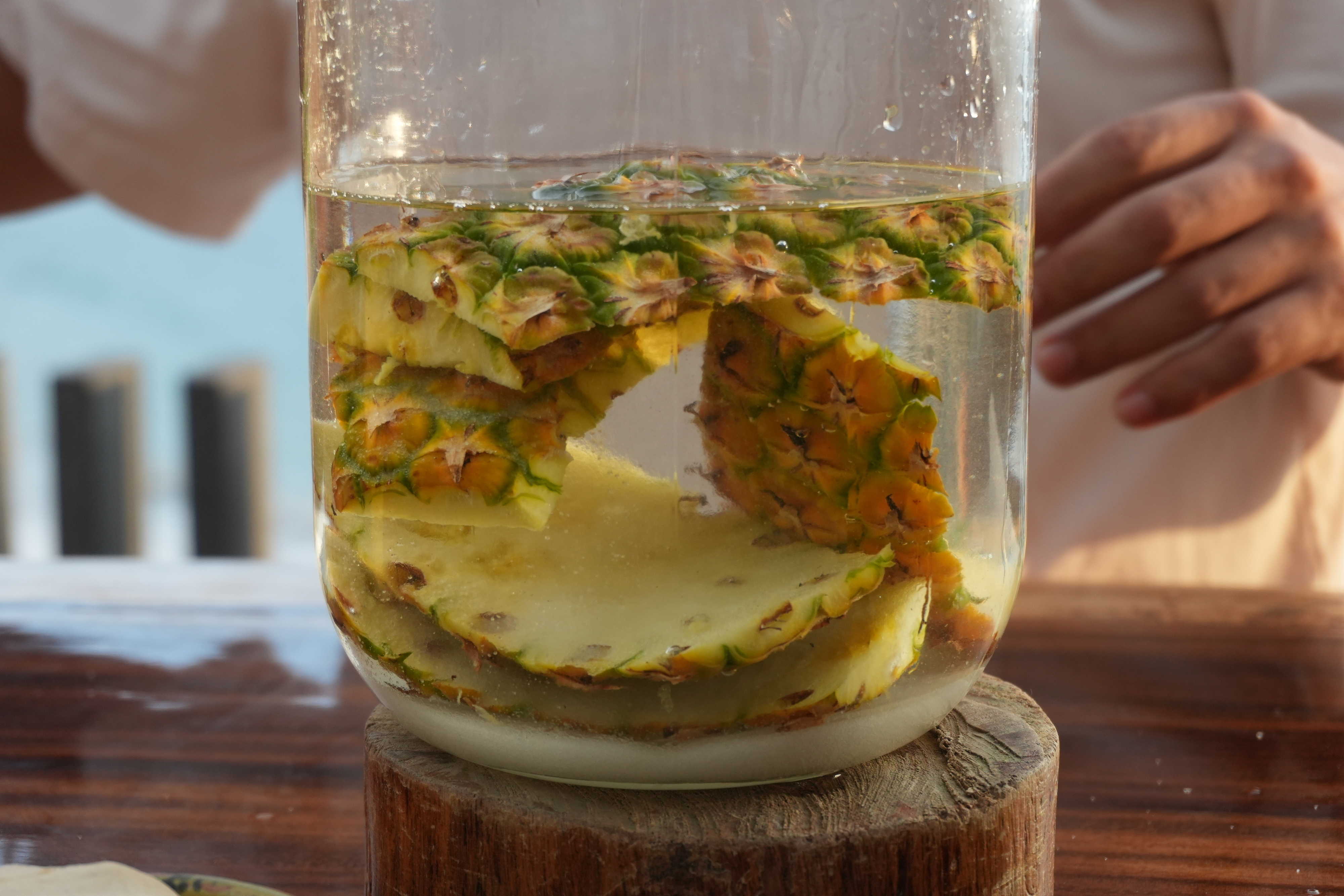 close up of pineapple rinds and sugar and water in jar