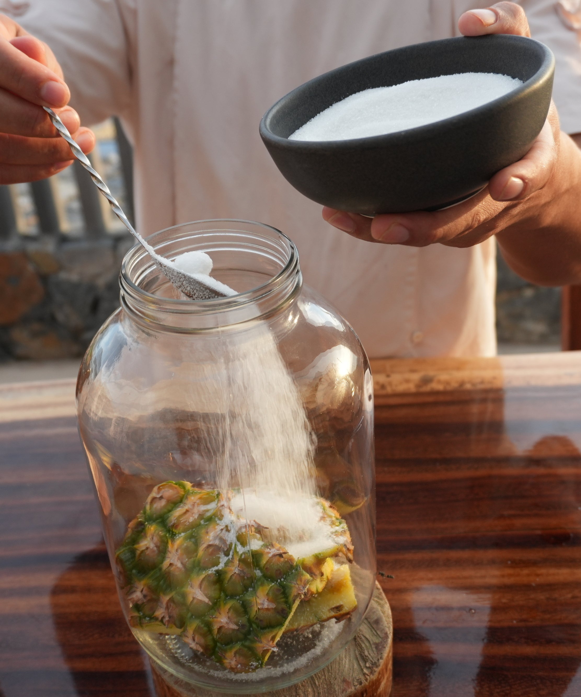 adding sugar into large jar of pineapple rinds