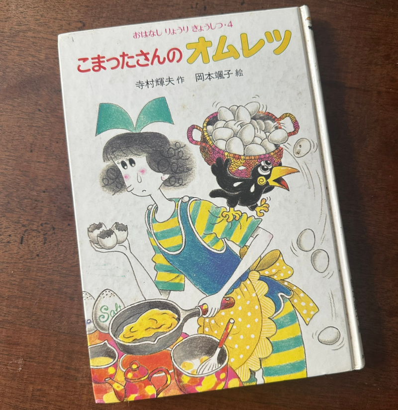 本の表紙にオムレツを作る人物のイラスト。タイトルは「こまったさんのオムレツ」。卵や料理道具が描かれている。