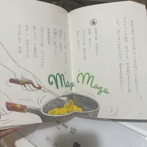 本を開いたページ。フライパンで料理をかき混ぜる絵と、調理手順に関するテキストが並んでいる。