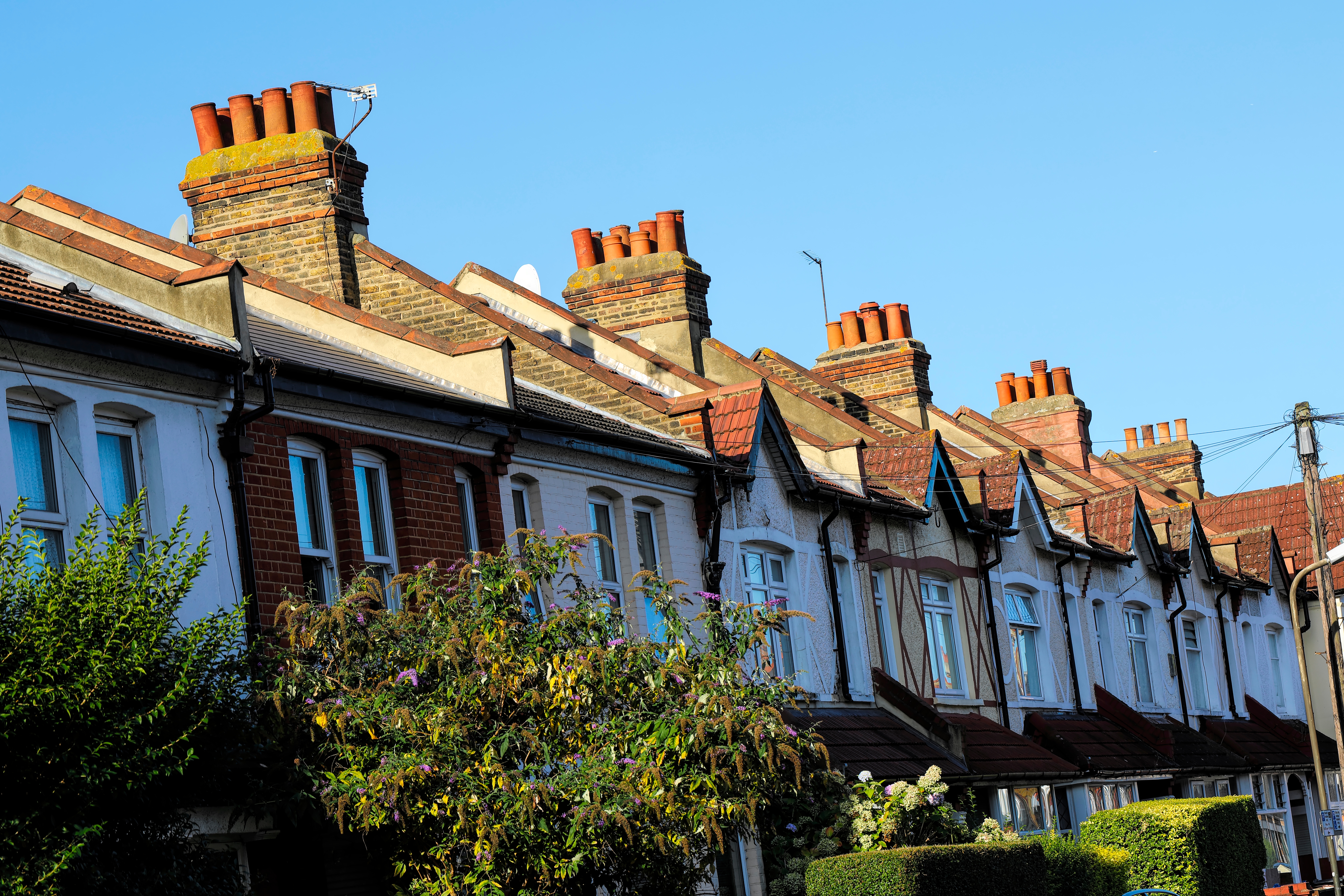 En rad med tilknyttede hus med fremtredende mursteinskorsteiner, under en klar himmel, som viser frem typisk boligarkitektur