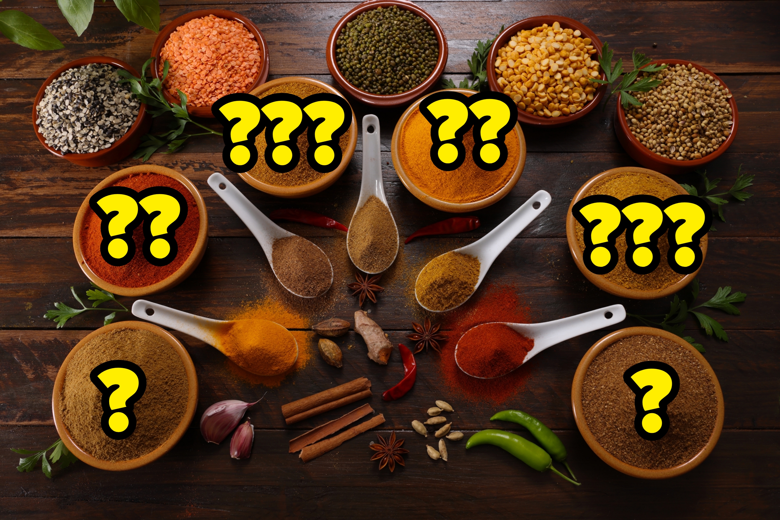 Assorterte krydder og urter anordnet i boller og på skjeer, inkludert chili, gurkemeie og spisskummen, med fersk hvitløk, ingefær og paprika på et trebord