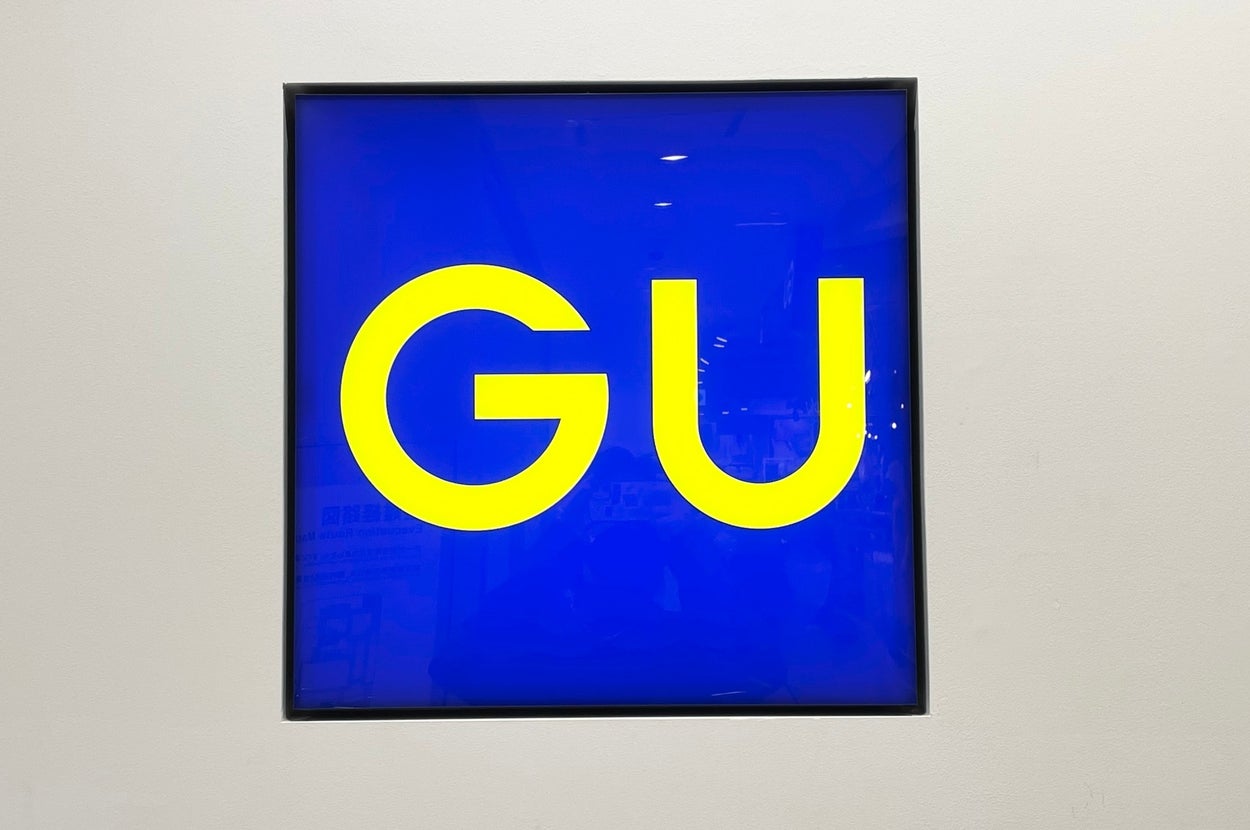 A store sign displaying the letters "GU" in bold text