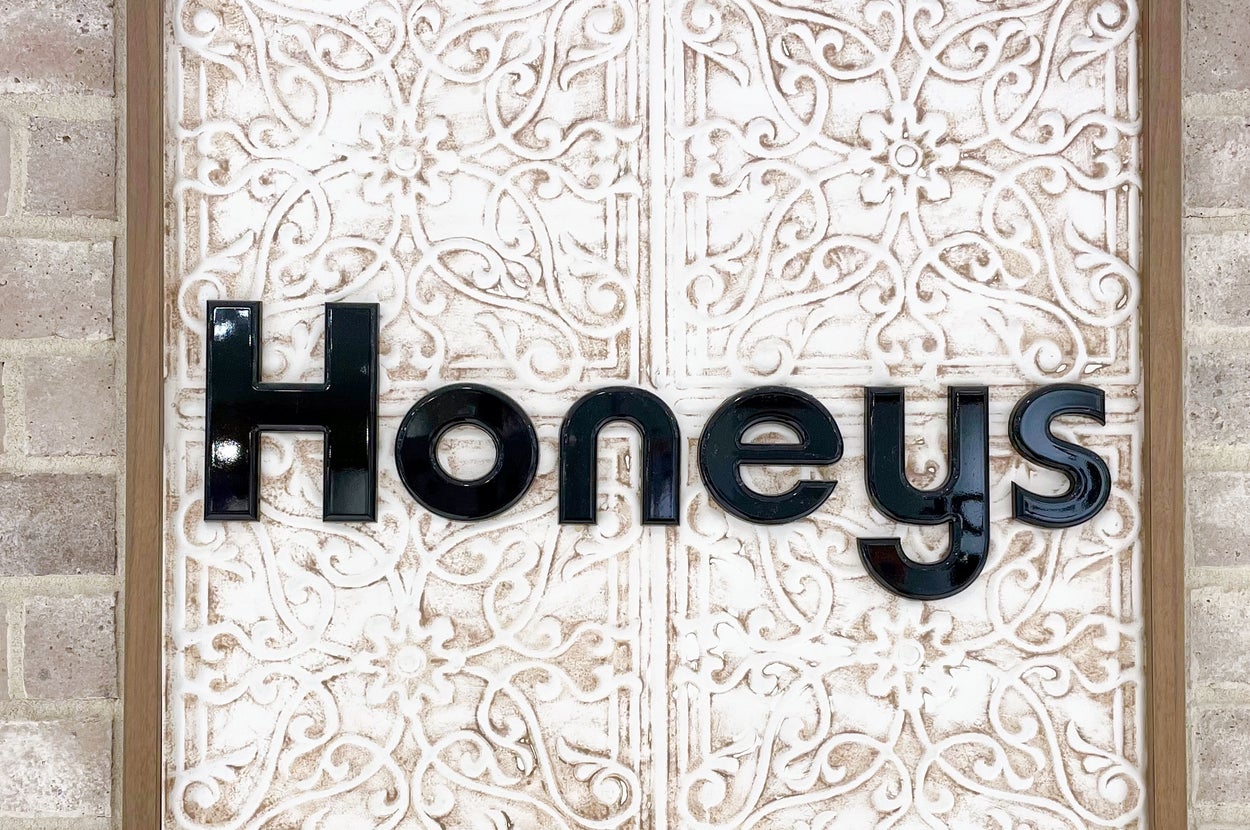 壁に取り付けられた「Honeys」のロゴサイン。装飾的な背景パネルが目立つ。
