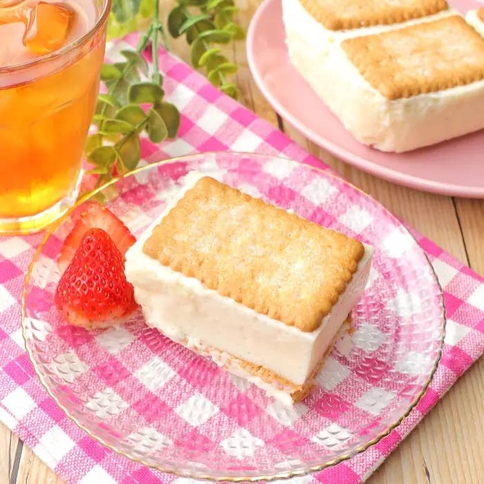 マシュマロとヨーグルトのムースがビスケットでサンドされている。横にカットしたイチゴとアイスティーのグラスが置いてある。
