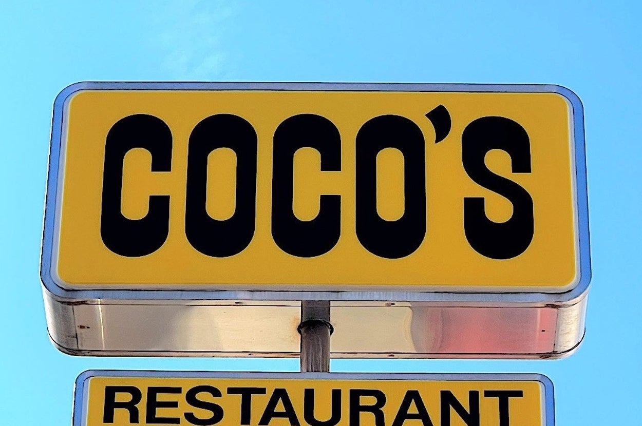 青空の下にある「COCO'S RESTAURANT」と書かれた看板の画像。