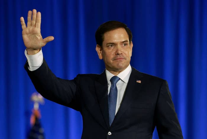 Person successful a suit waves during a ceremonial event. A U.S. emblem is faintly disposable successful the background