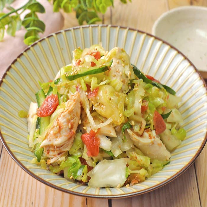 チキンと野菜の和え物が盛られた皿。キャベツ、キュウリ、トマトが含まれている。
