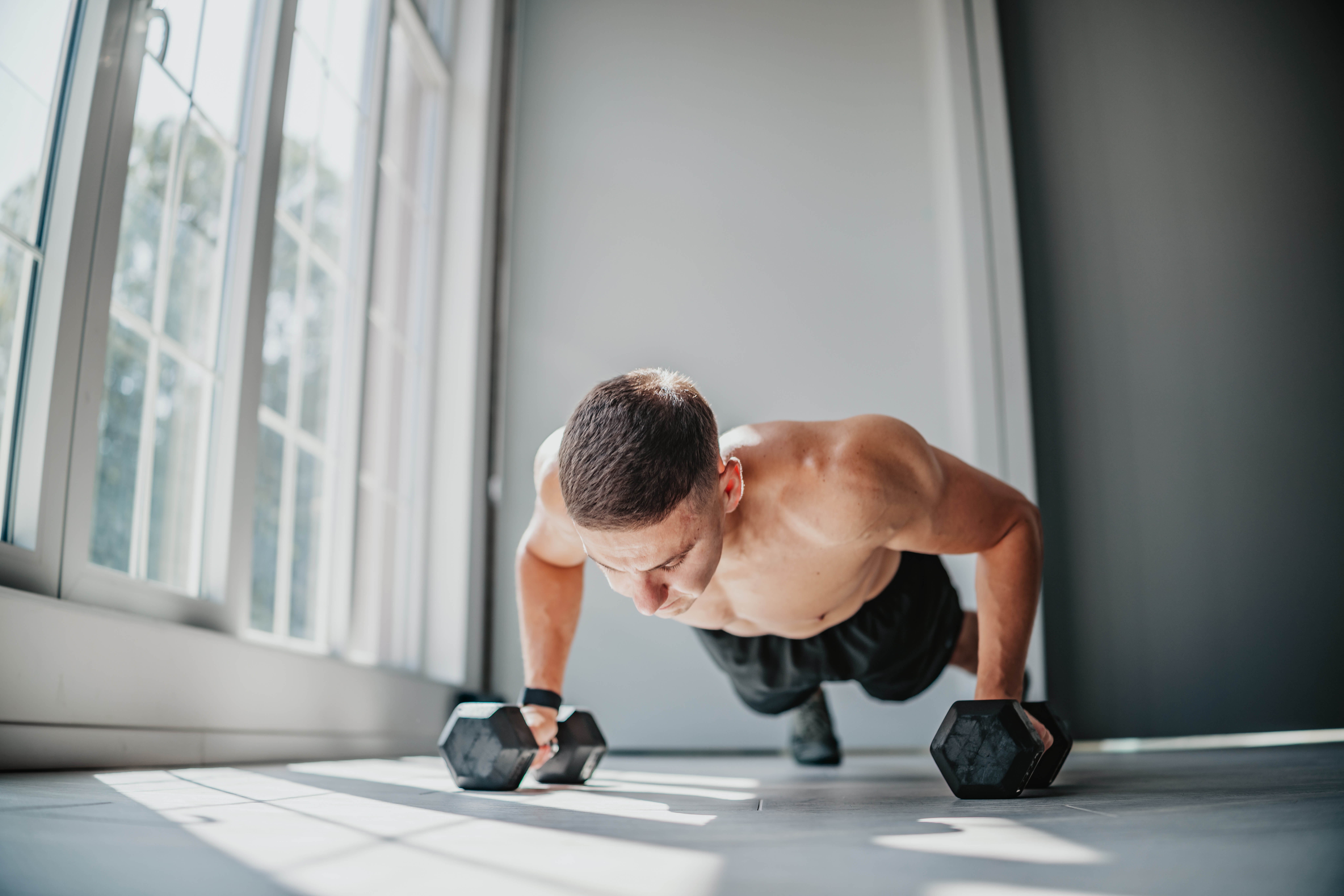 En person som gjør push-ups innendørs ved hjelp av manualer, fokusert på treningsform og styrke