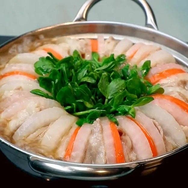 鍋に均等に並べられた野菜と肉が魅力的に盛り付けられている。中央には新鮮な葉物野菜があります。