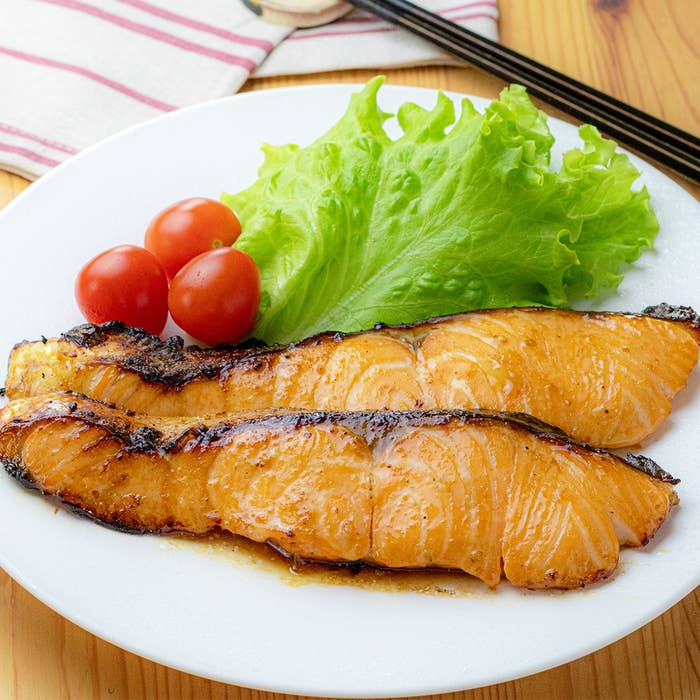 皿に焼きサーモン、レタス、ミニトマト。シンプルな食事のイメージ。