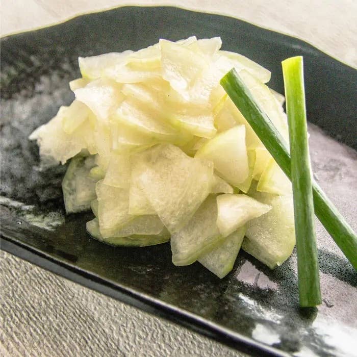 冬瓜のさっぱり浅漬け。お皿に盛られた薄切りの冬瓜の山と隣に立てられた長ネギの細切り。