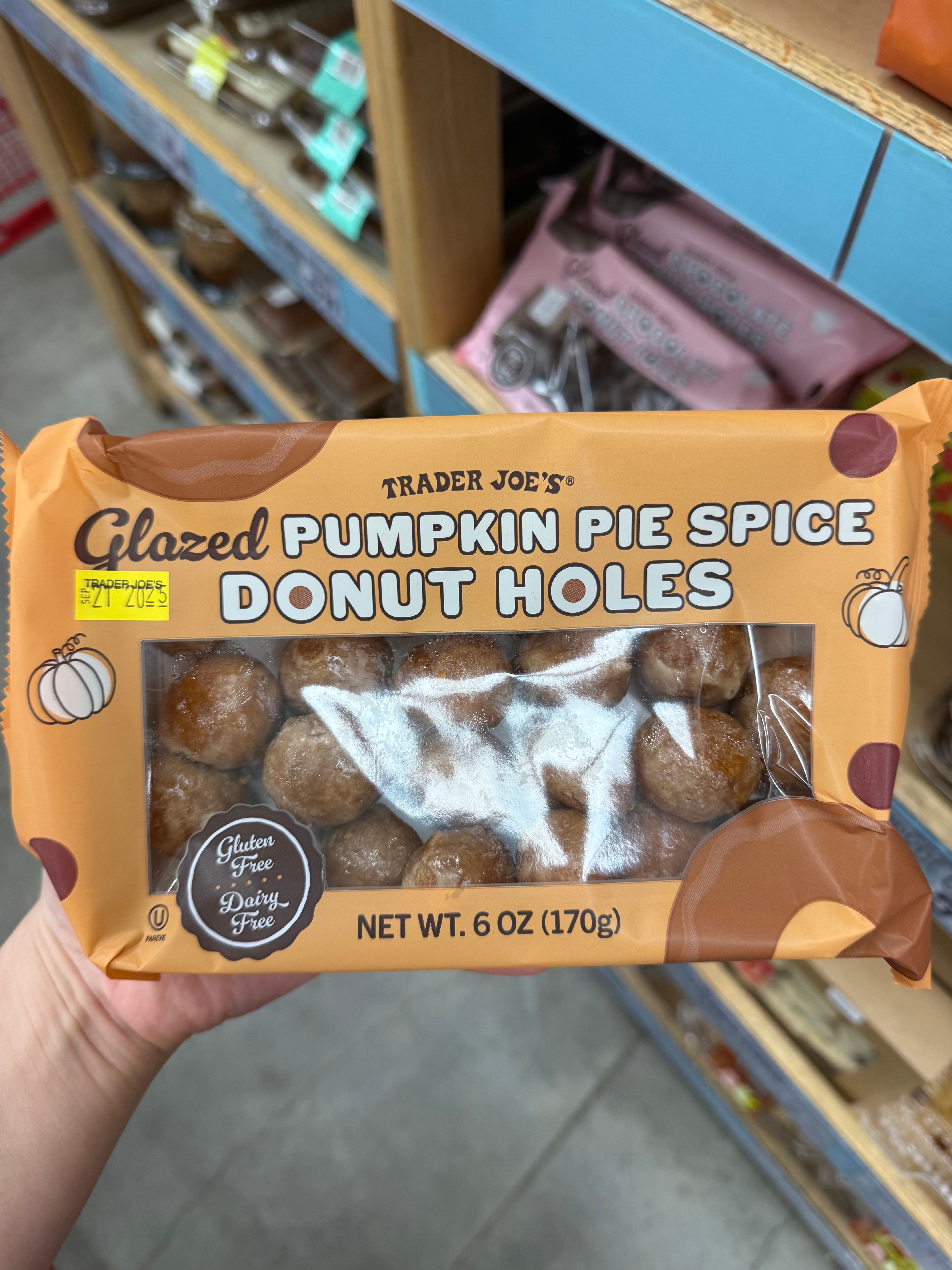 Trader Joe's Glazed Pumpkin Pie Spice Donut Holes package in a store aisle; label indicates gluten and dairy-free