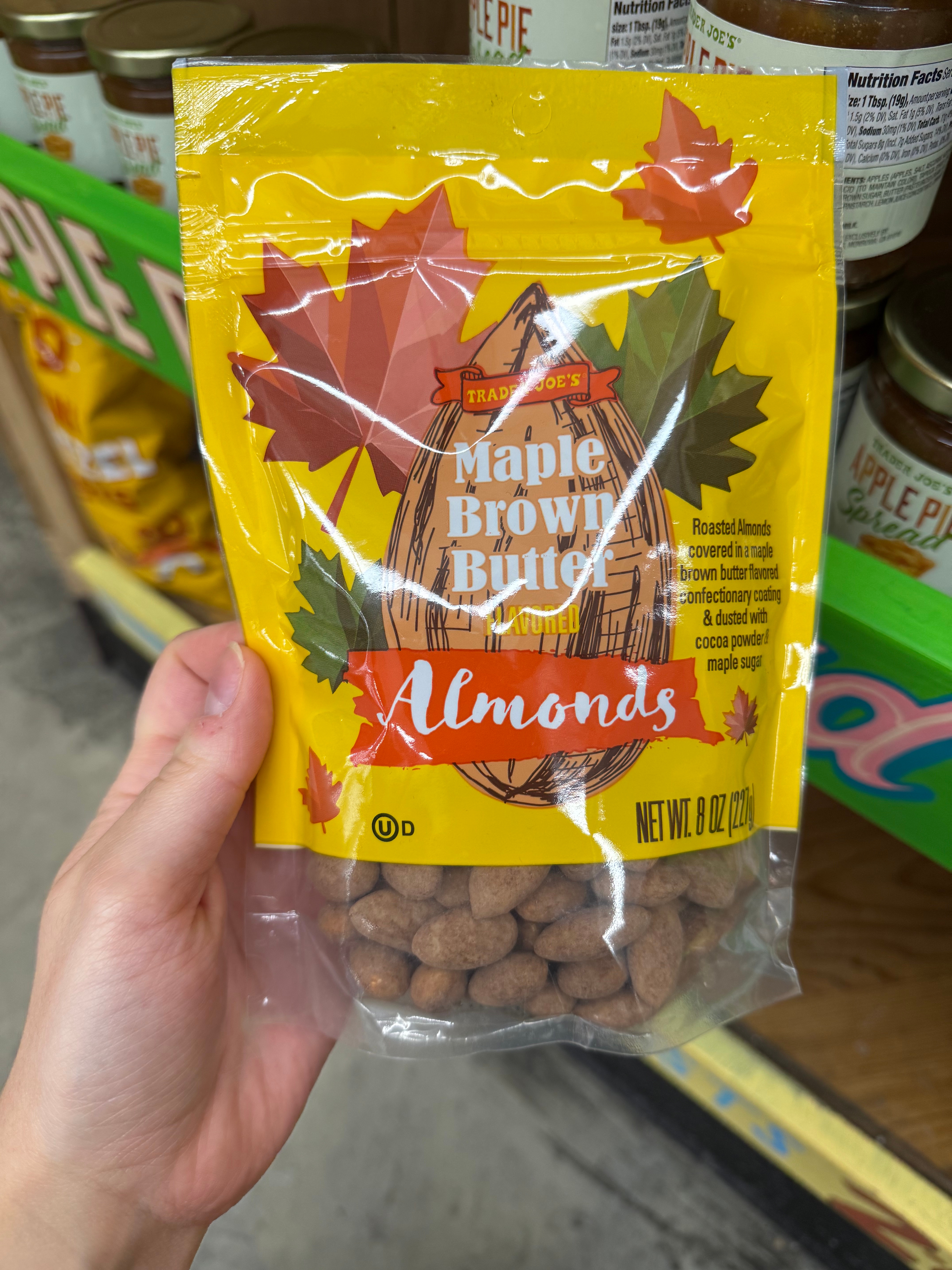 Bag of Trader Joe's Maple Brown Butter Almonds on a store shelf, featuring a fall leaf design and maple flavor description