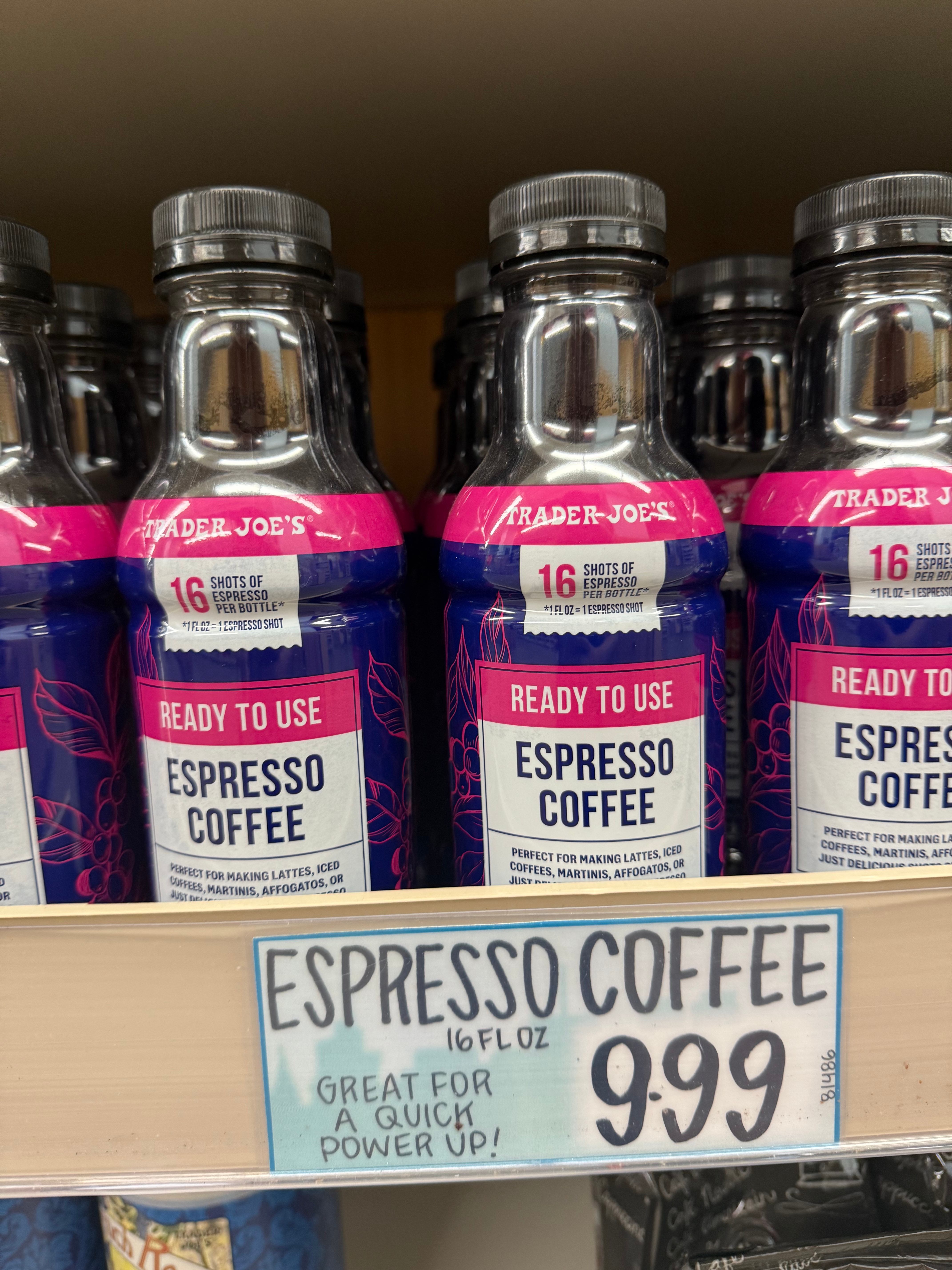 Bottles of ready-to-use espresso coffee on a shelf, with a store sign displaying 16 fl oz bottles for $9.99, noted as a quick power-up drink
