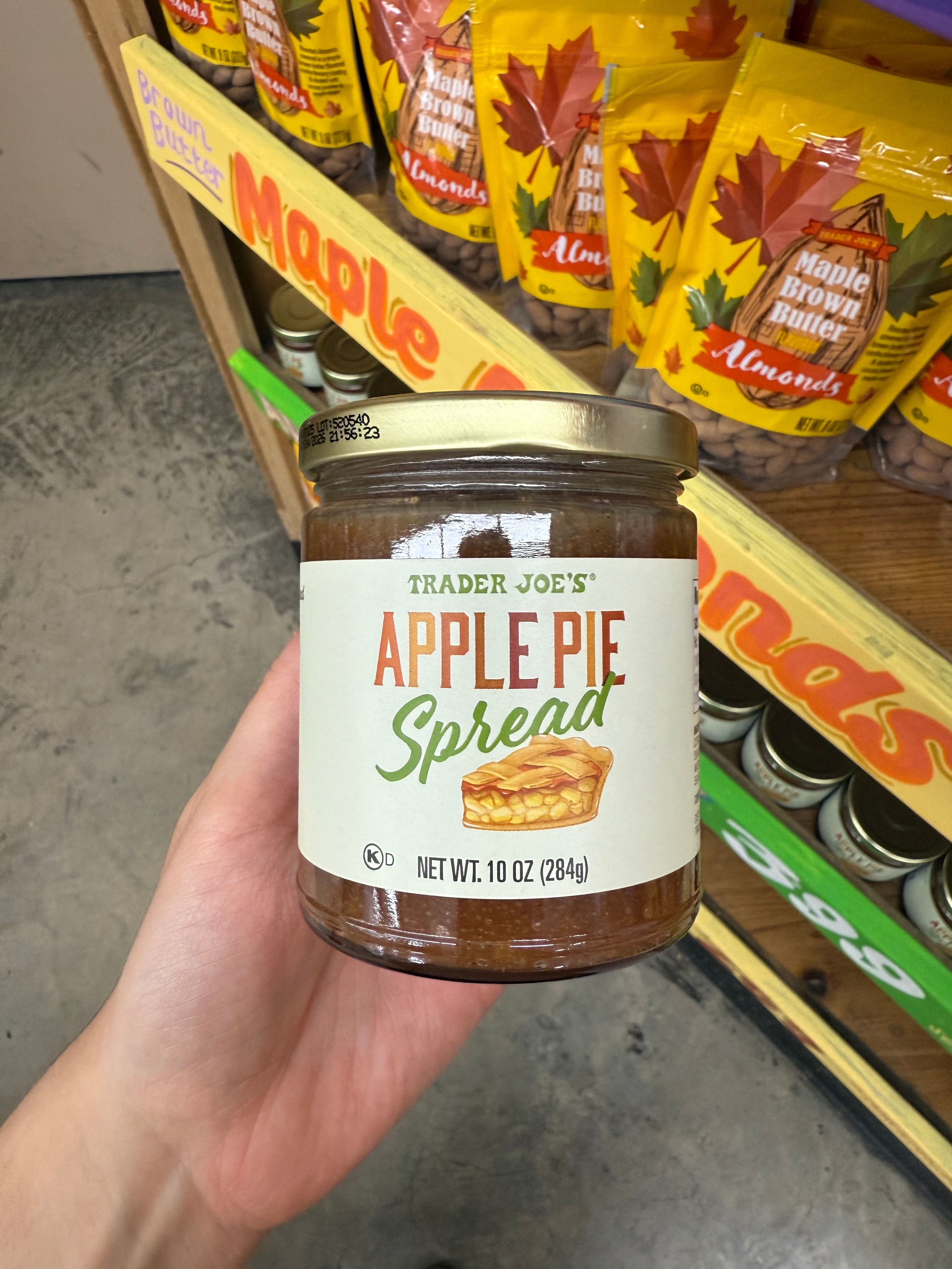 Person holding a jar of Trader Joe's Apple Pie Spread in a store aisle