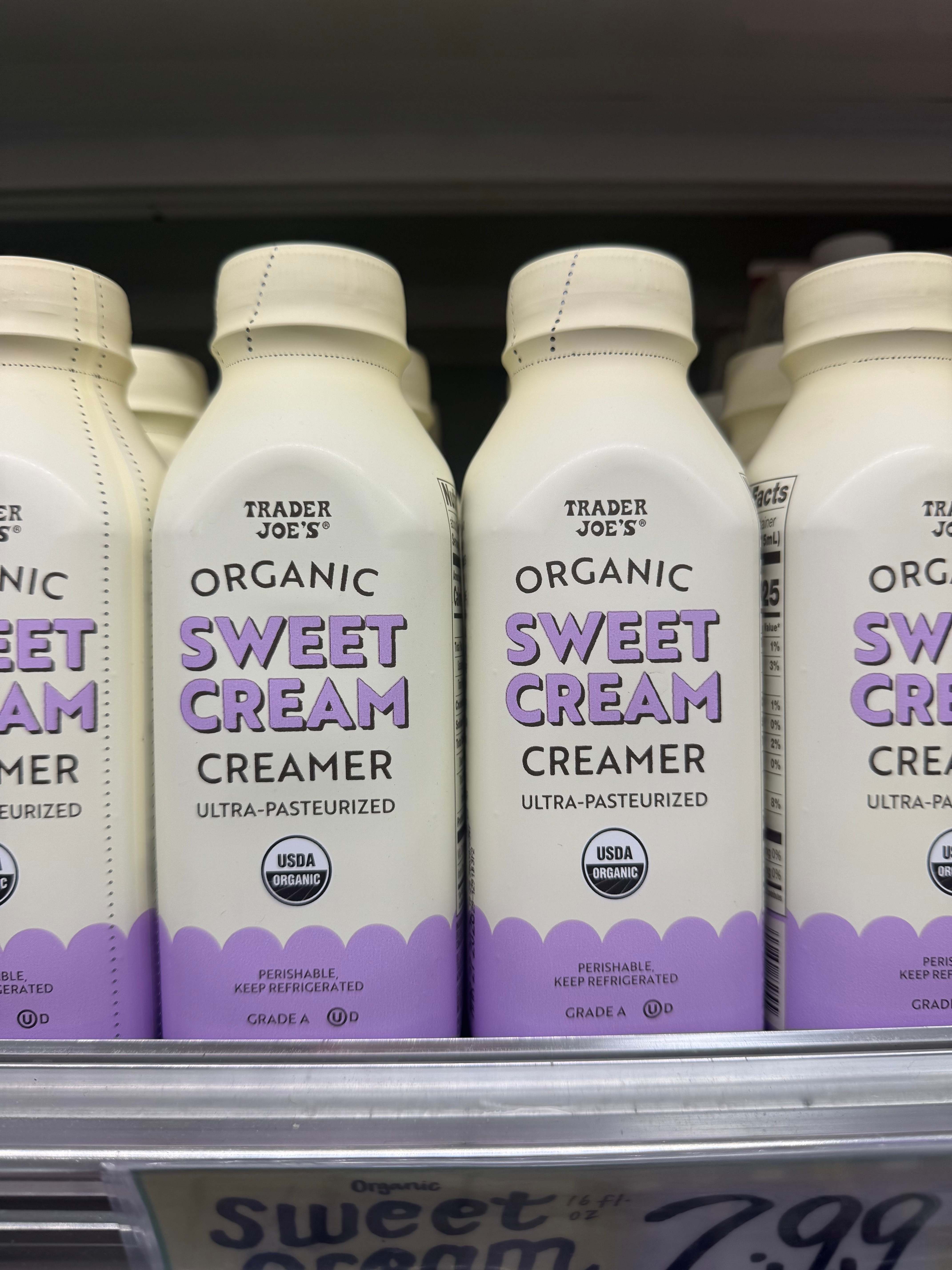 Trader Joe's Organic Sweet Cream Creamer bottles on a grocery shelf, labeled as ultra-pasteurized and USDA organic