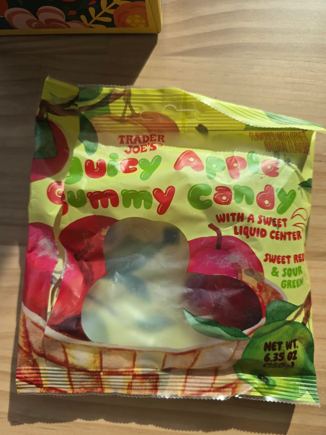 Bag of Trader Joe's Juicy Apple Gummy Candy featuring apples and text about sweet liquid centers, net weight 6.35 oz