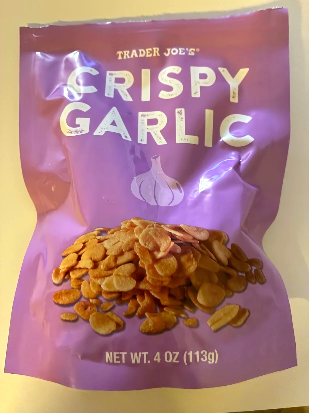 Bag of Trader Joe's Crispy Garlic chips, 4 oz (113g). Packaging depicts sliced garlic chips below brand and product name