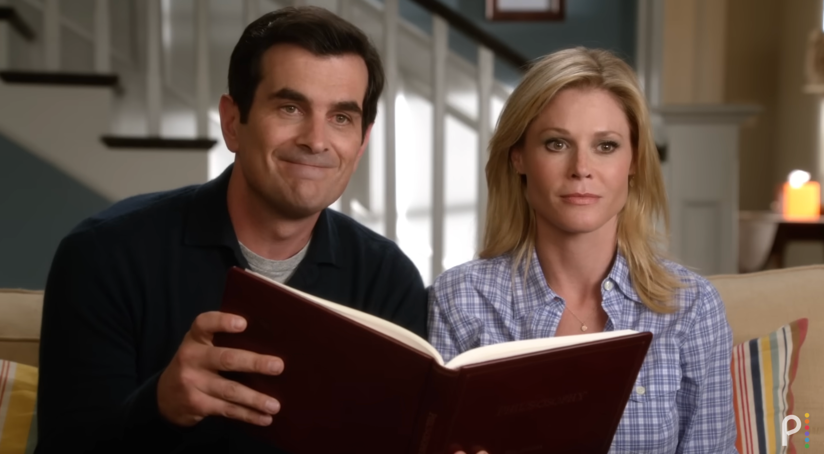 Foreldrene fra moderne familie sitter sammen på en sofa. Phil leser fra sin Philososofy -bok