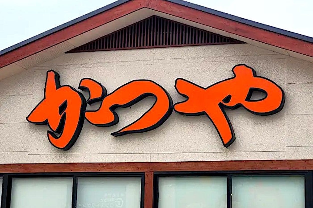 Building with a sign displaying stylized Japanese characters above several windows