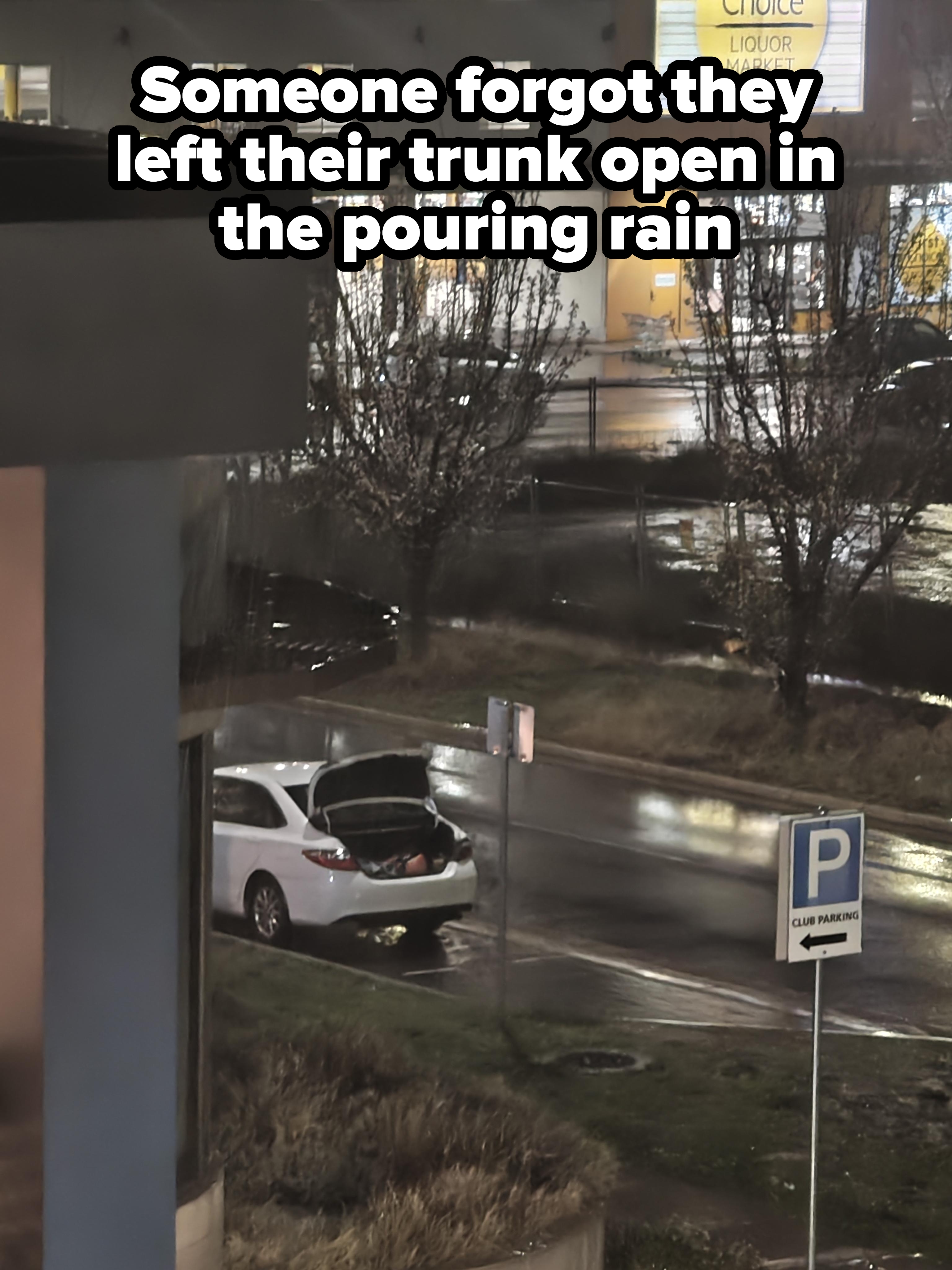Car parked outside a store with trunk open on a rainy night