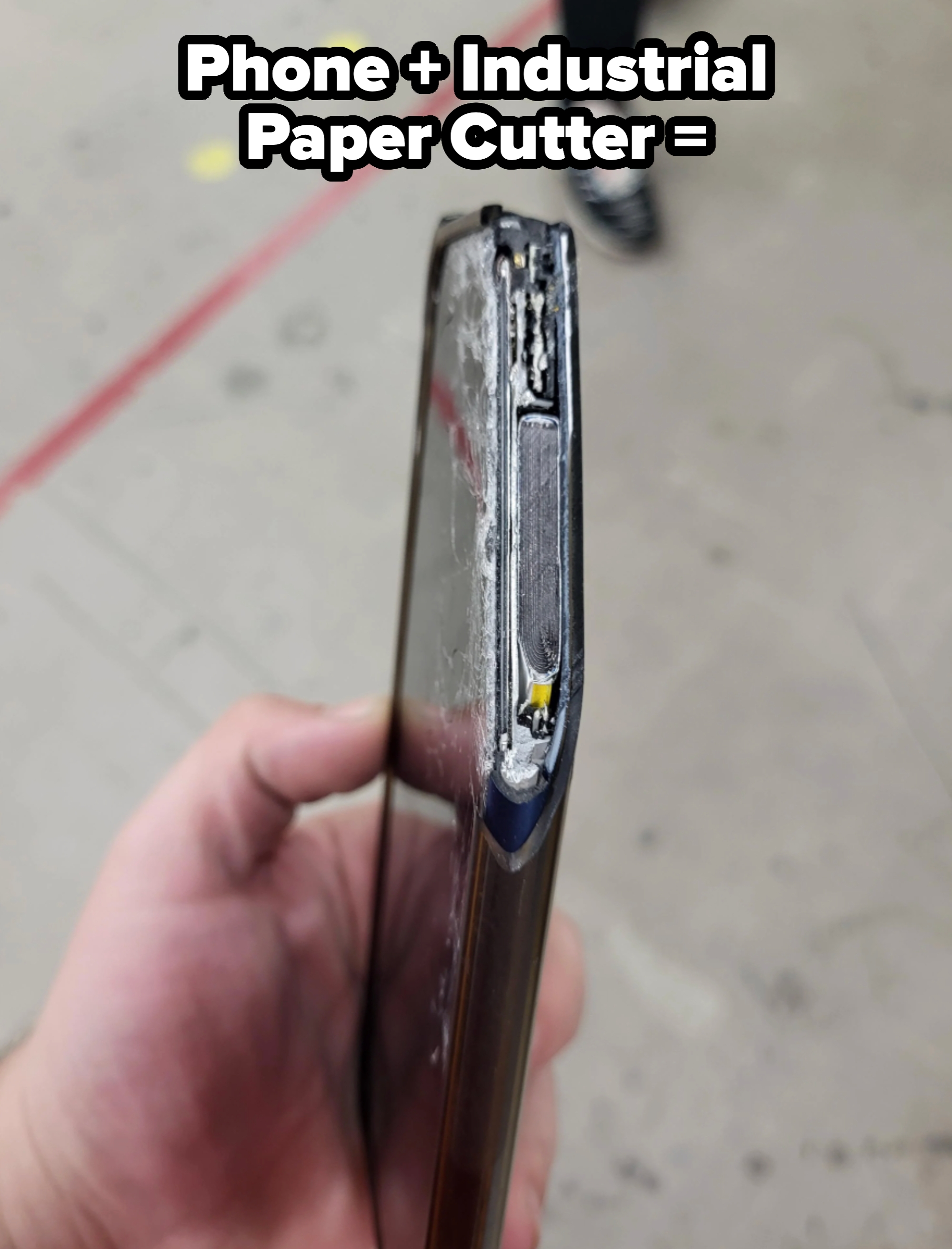 A person holds a damaged phone with a visibly bent frame and exposed internals, suggesting it has been severely impacted or crushed