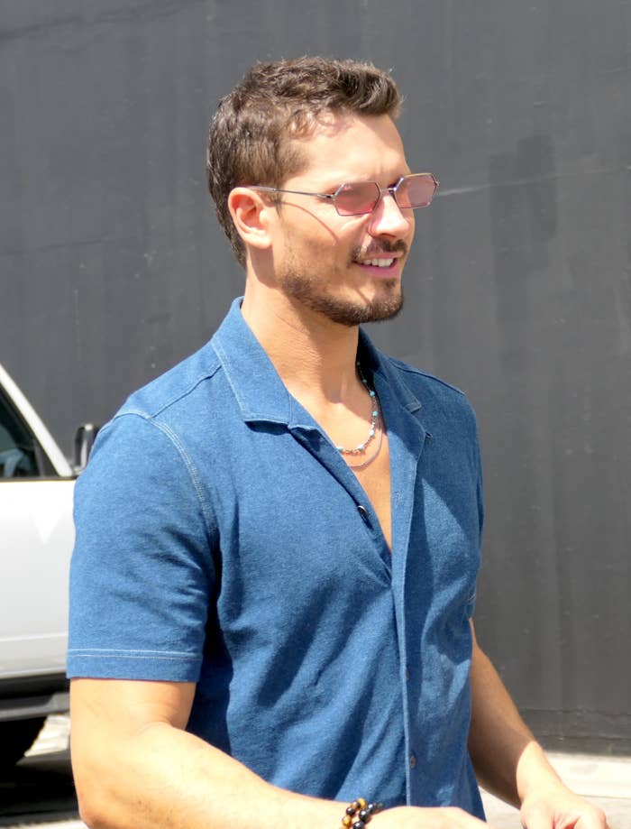 Gleb Savchenko wearing sunglasses and a casual short-sleeve garment smiles portion lasting outdoors